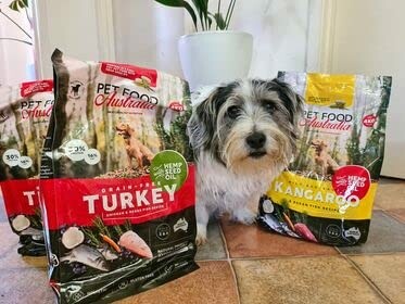 Dog sitting with Pet Food Australia bags of turkey and kangaroo flavor.